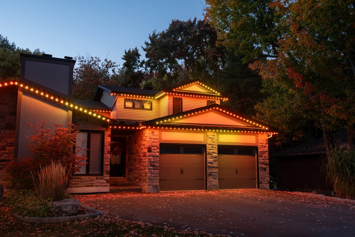Stone home glowing with warm orange permanent roofline lighting